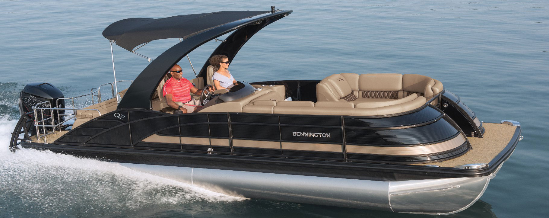 Group of people on a Bayliner boat pulling a man on a wakeboard on a sunny day on the lake.